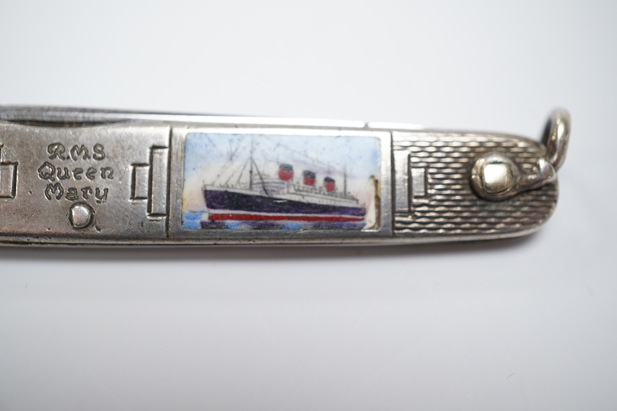 A George V engine turned silver and enamel pocket knife, decorated with R.M.S Queen Mary, the blades lifted by the handles, George Ibberson & Co, Sheffield, 1936, 76mm. Condition - poor to fair